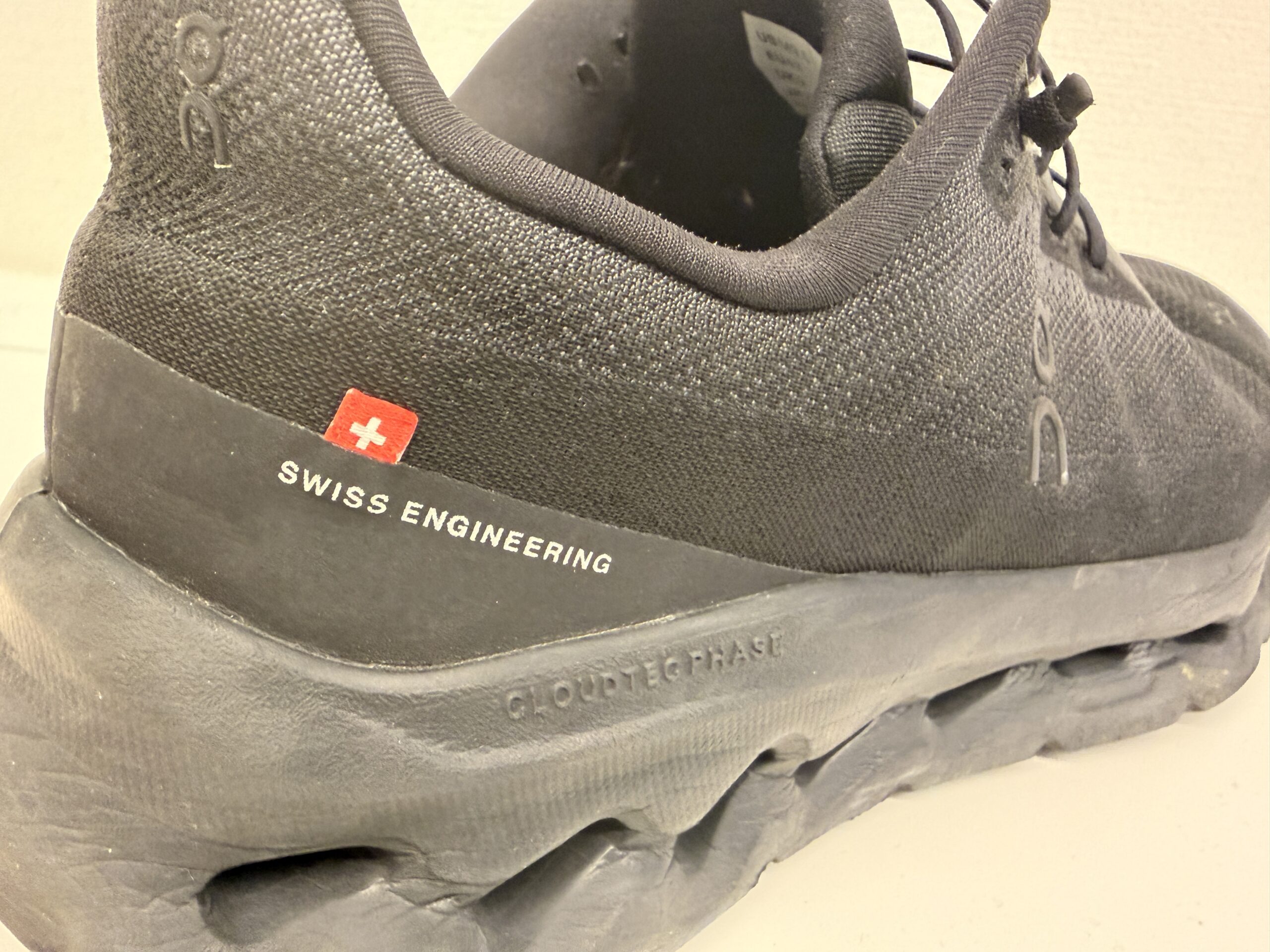 黒いスニーカーのかかと部分に「SWISS ENGINEERING」と赤いスイス国旗のマーク。靴の周りは白背景。